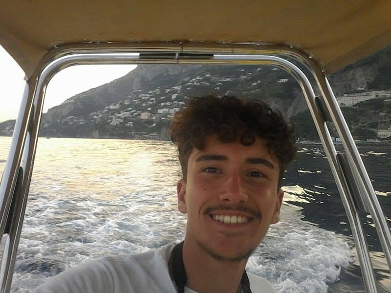 A young man aboard a motorboat cruising along the coast